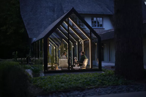 Koppel zit 's avonds in een verlicht tuinkamer
